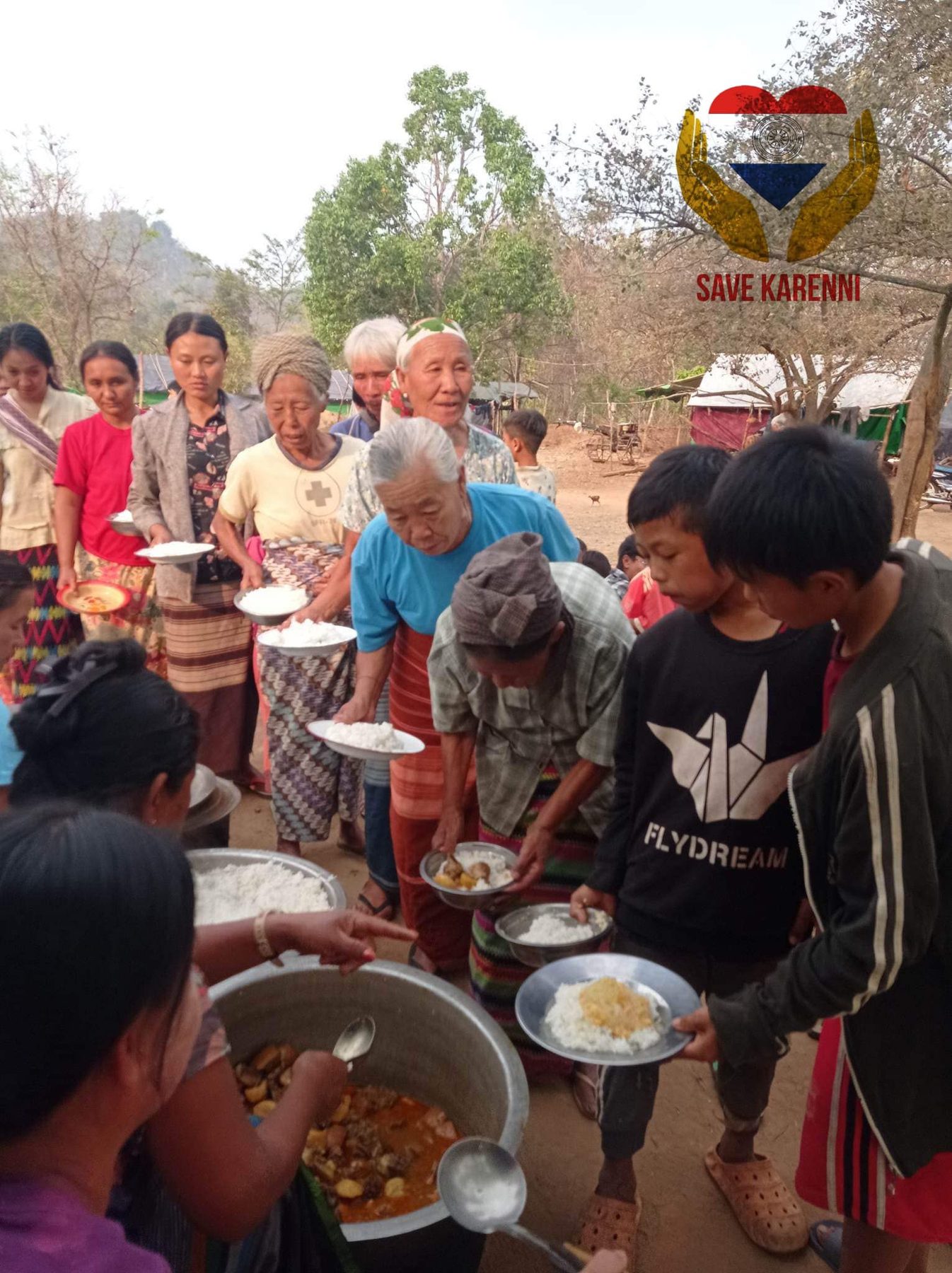 Volunteers serve rice and curry from large pots to a line of elderly people.