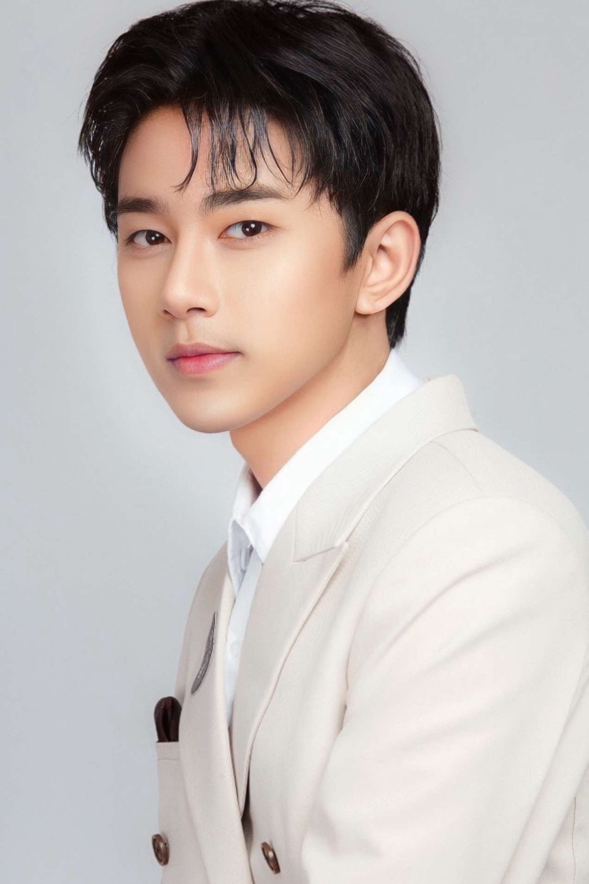 Studio portrait of Wai Yan Aung in a cream double-breasted jacket and white shirt, against a pale grey background.